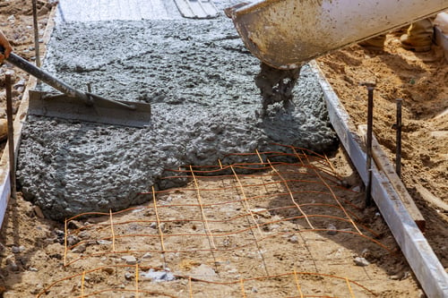 Fresh concrete being poured over a rebar grid for a new slab